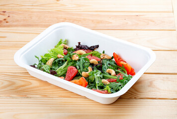Juicy salad with grapefruit and arugula. Healthy food. Takeaway food. On a wooden background.