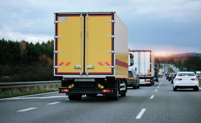 A yellow cargo truck of a postal delivery company while driving on a European highway. Postal service. Door-to-door delivery of the goods.