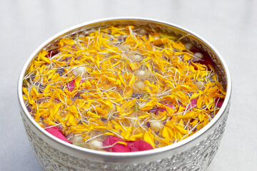 Water with jasmine flower, marigold petals and rose petals in silver bowl. Thai tradition, Songkran...