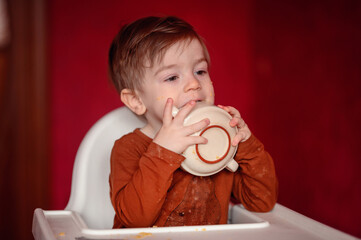A hungry toddler affectionately 'kisses' the bottom of an empty bowl, capturing a moment of...