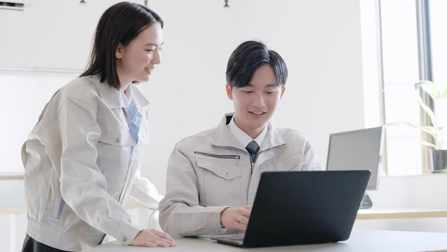 パソコンを見る作業着を着たビジネスマンたち
