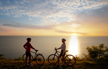 Fototapeta premium Two women with bicycles on the sea or lake shore