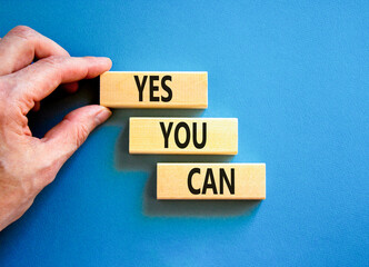 Motivational and Yes you can symbol. Concept words Yes you can on beautiful wooden blocks. Beautiful blue background. Businessman hand. Business motivational and Yes you can concept. Copy space.