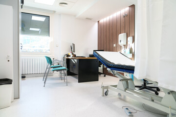Clean clinic room with examination bed and desk area for consultations.