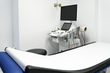 Empty hospital ultrasound room with modern sonography equipment and an exam table.