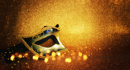 Photo of elegant Venetian mask over glitter gold background