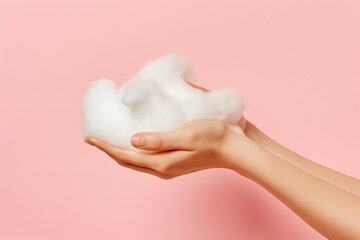 Womans hands play with sudsy soap foam on a soft pink background