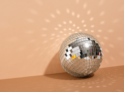 Shiny mirrored disco ball by the wall. Copy space for text. Reflections in wall. Party night.