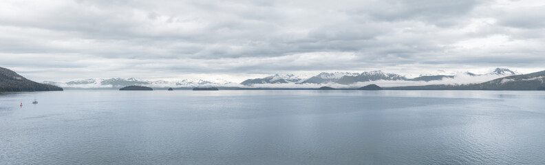 Fototapeta na wymiar Panorama of clouds and mist around the snow covered mountains of Frederick Sound in Alaska, USA