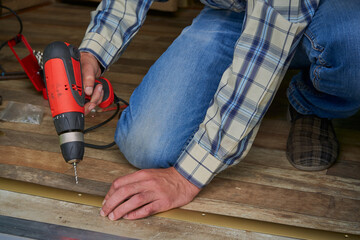man with a drill installing floor thresholds, drill a hole in the threshold for installation, the...