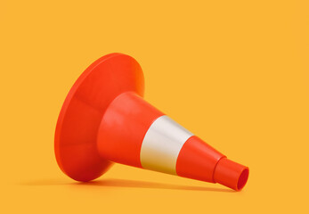 Orange construction cone lies on a yellow background. Industry details.