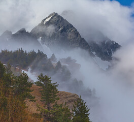 snowbound rocky mountain chain in dense mist and clouds