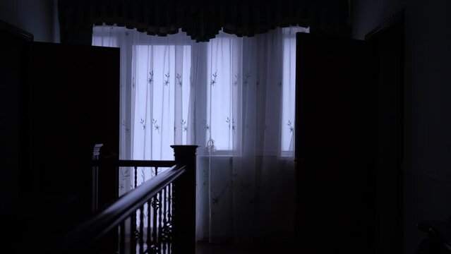 A dimly lit corridor with open doors and tulle on the windows