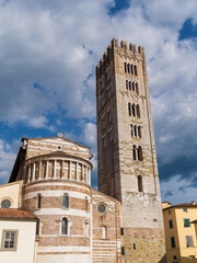 Basilica of San Frediano (St Fredianus) romanesque apse with medieval bell tower among clouds, in Lucca historical center