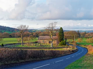 Foto op Canvas The rural A683 road passing the historic Church of Holy Ghost set in a valley in the Yorkshire Dales National Park, on a cold February evening. © Julian