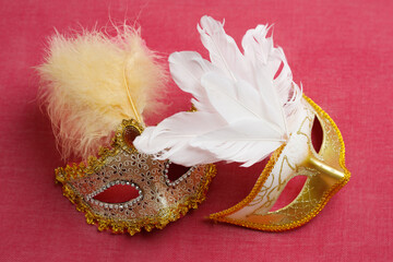 Beautiful white and gold carnival masks on a pink background. Purim, Mardi Gras holiday concept.