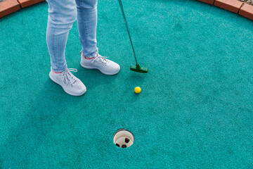 Golfer playing adventure or mini golf and trying putting ball into hole. Sports and leisure activity