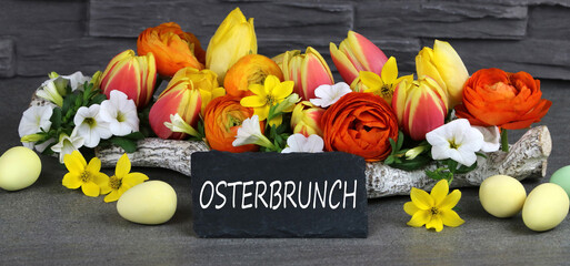 Osterbüfett auf eine Tafel geschrieben mit Blumen und Ostereiern dekoriert.