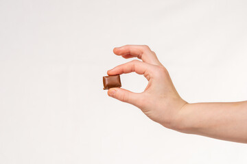 a piece of chocolate in hand on a white background