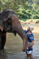 Young guy showering an elephant in a sanctuary in thailand