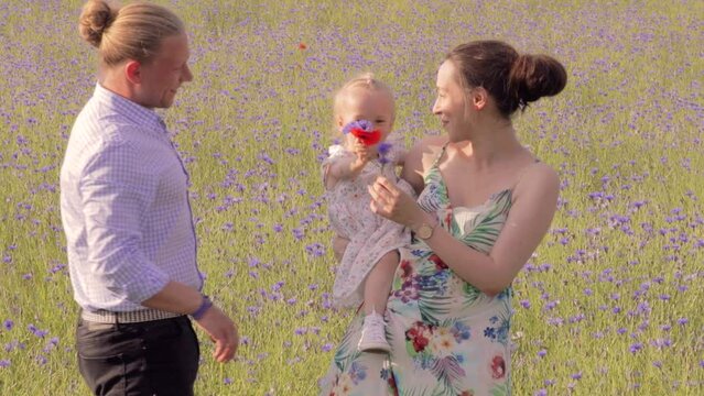 Happy first-time family enjoying their adorable little girl in a field of flowers