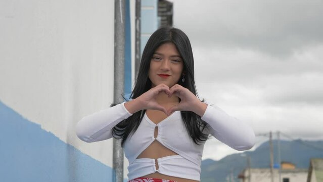 A beautiful Latina girl folds her hands to form a love symbol on a rural road in the city of Machachi, Ecuador