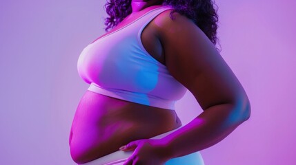 A pregnant woman in a white tank top standing against a purple background with her hand on her hip showcasing her belly. - Powered by Adobe