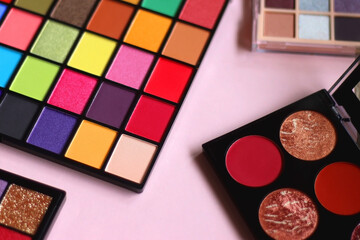 Various colorful eyeshadow palettes on bright pink background. Selective focus.