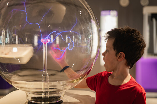 Curious boy exploring plasma globe at a science museum