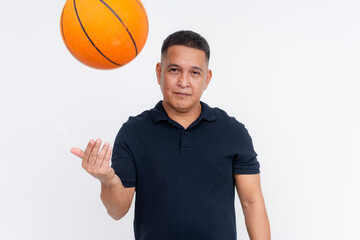 A middle aged asian man skillfully tossing a basketball while looking confidently at the camera....
