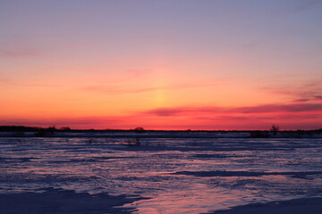 Crimson dawn over meadows in winter
