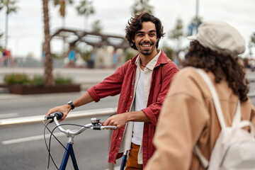 A young man on the street with bike is smiling at his friend.