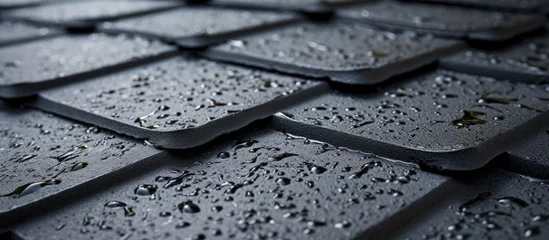 Fotobehang A close-up black and white shot of raindrops collected on a textured stone coated bituminous roof, showcasing the protective layer against moisture. © AkuAku