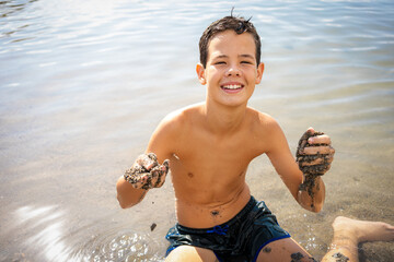boy sitting on sandy beach near sea having fun during sunny day © Danko