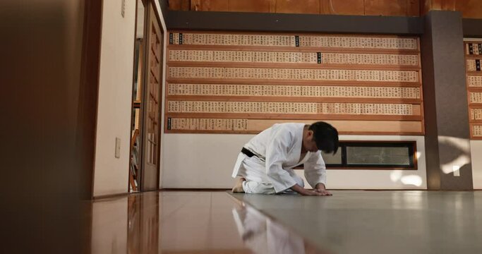 Man, student and bowing for aikido in dojo with greeting for respect, tradition and culture in class. Martial arts, person and sitting for discipline, worship or expression in practice with fitness