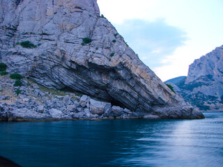A rock with a distinct soil texture stands above calm water. Picturesque mountain landscape at...