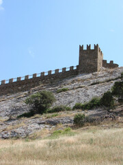 A medieval fortress on a stone rock against the background of a clear blue sky.