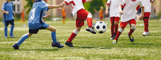 Soccer Youth Teams Play Outdoor Tournament. Young Soccer Players Competition. Boys Kicking Football Ball. Soccer Stadium in the Background - obrazy, fototapety, plakaty