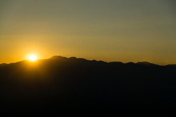The sun sets among the mountains.