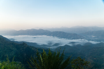 Misty mountain landscape, clear blue cloudless sky and layers of hills. Cold mood.
