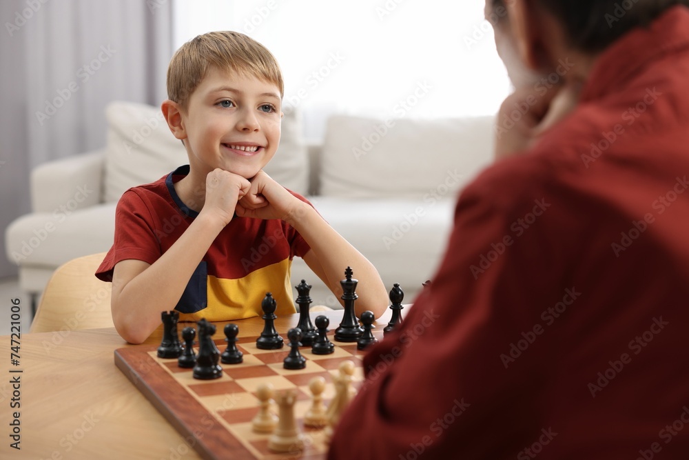 Canvas Prints Little boy playing chess with his grandfather at table in room