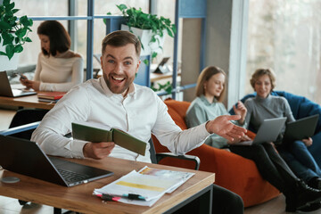By the table with laptop. People are working in the office with bean bags chairs in it