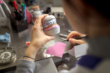 Dental technician makes a denture for the patient. Prosthetics and Production of Model Teeth in...