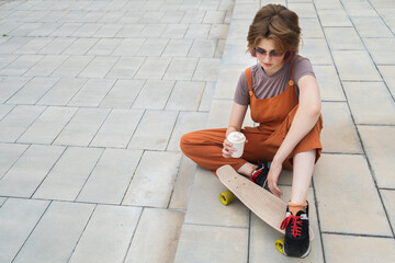 Gen Z skater girl sits on steps with blank coffee container in her hands.