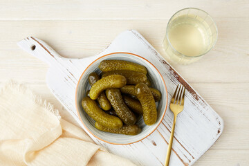 Marinated gherkins in a bowl and pickled juice or cucumber pickle, on a wooden background. Homemade...