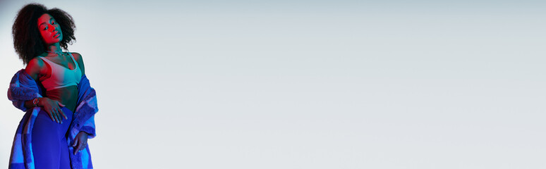 sexy african american woman in fashionable stylish faux fur looking at camera in lights, banner