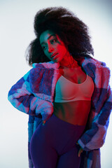 sexy chic african american woman in vibrant faux fur and bra looking away in red and blue lights