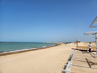 Fototapeta premium Dwarka, Gujarat India - Feb 21 2024: Shivraj Beach (Blue flag beach) - Long, flat white-sand beach with rocky outcrops and calm waves, plus wooden, grass-roofed umbrellas in Gujrat.