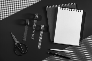 Notepads and pens, deco tapes and decorative paper and scissors on a black background. Concept of...