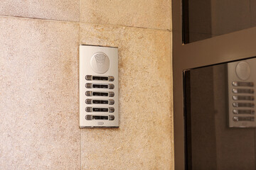 Outdoor intercom outside a residential building with empty name tag cards. Silver modern doorbells with blank nameplates suitable for adding text. European intercom communication system